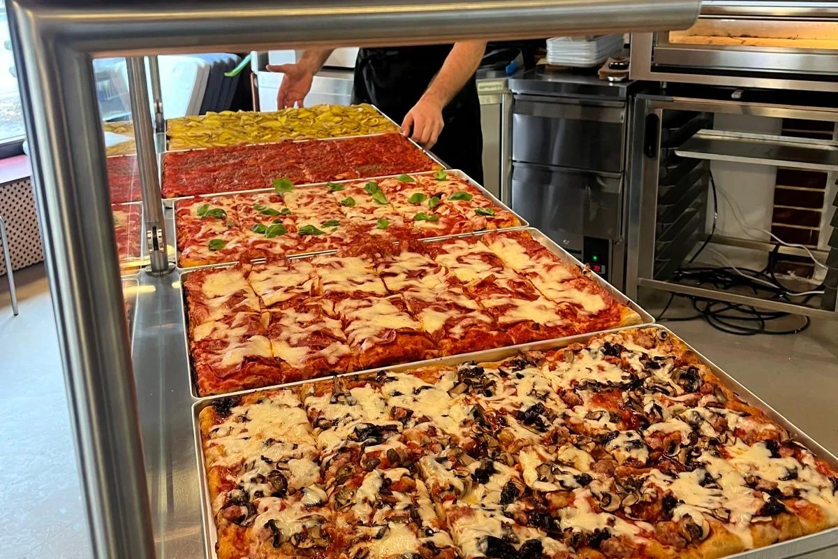 Five trays of pizza al taglio in the counter