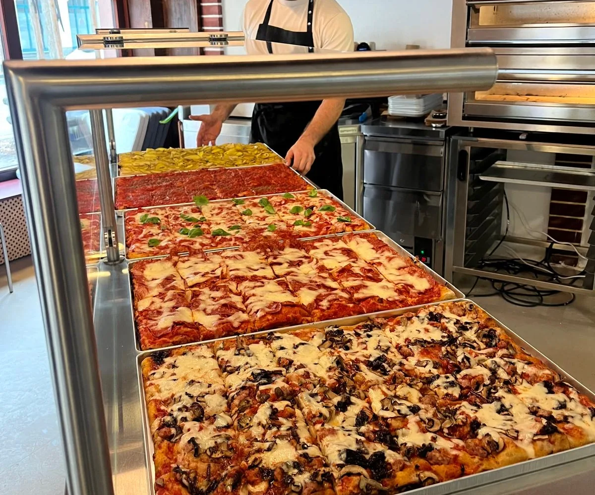 Counter with five trays of pizza al taglio
