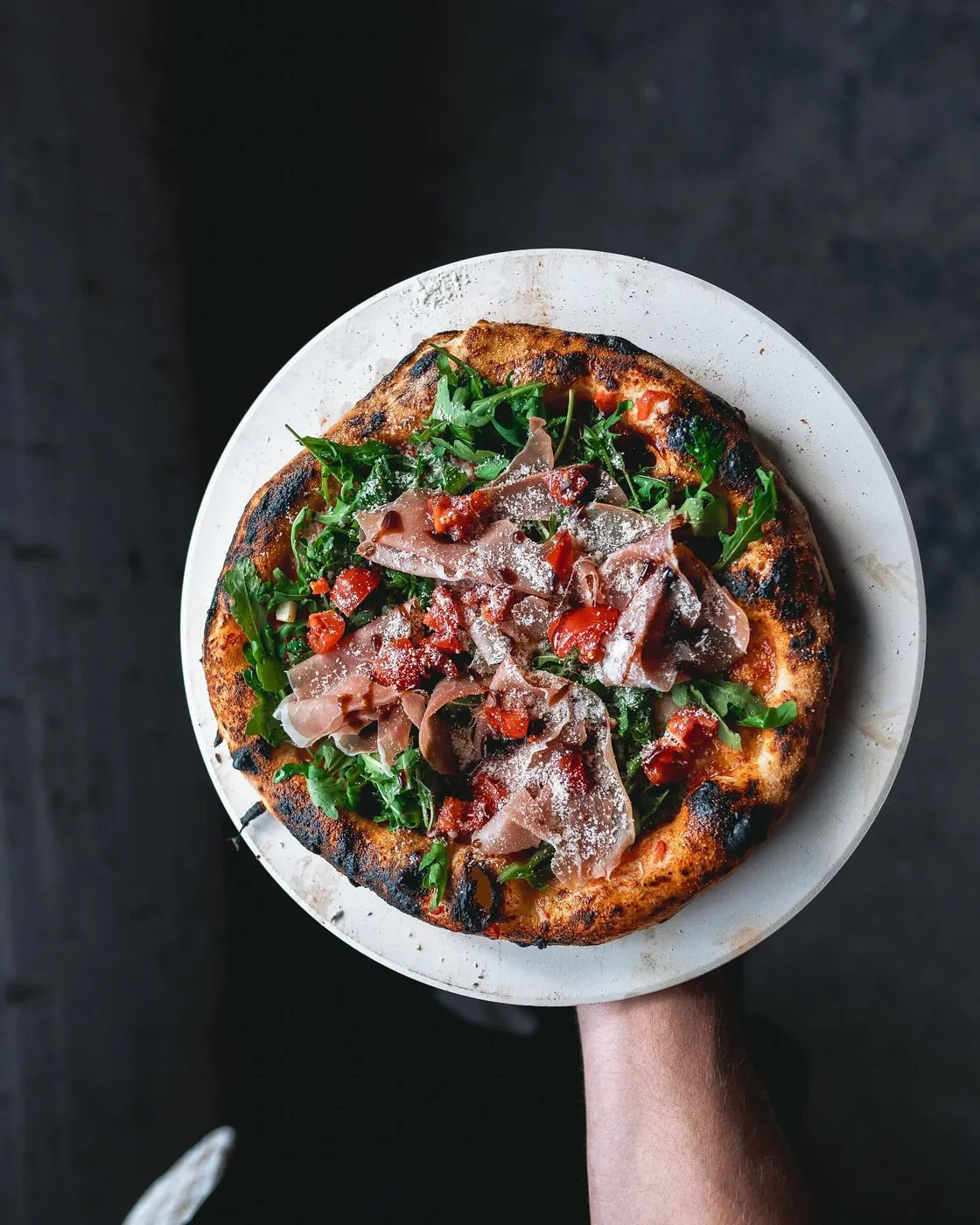 Pizza with prosciutto and rocket on a plate