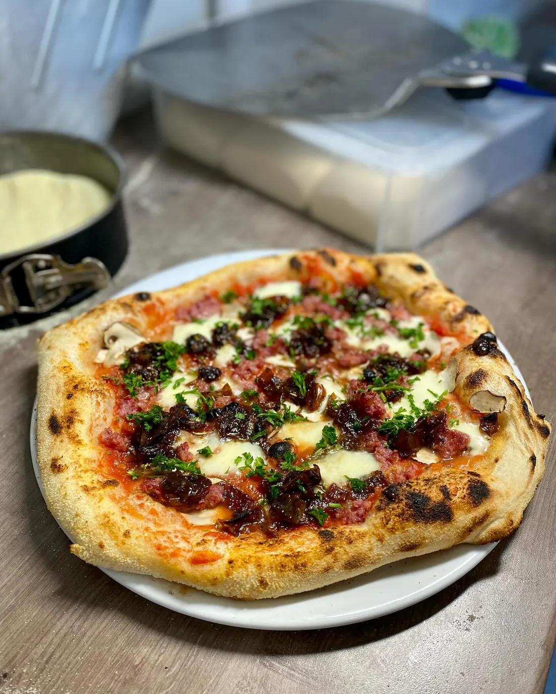Pizza mit Salsiccia piccante, Champignons, hausgemachter Zwiebelmarmelade, Petersilie und Mozzarella
