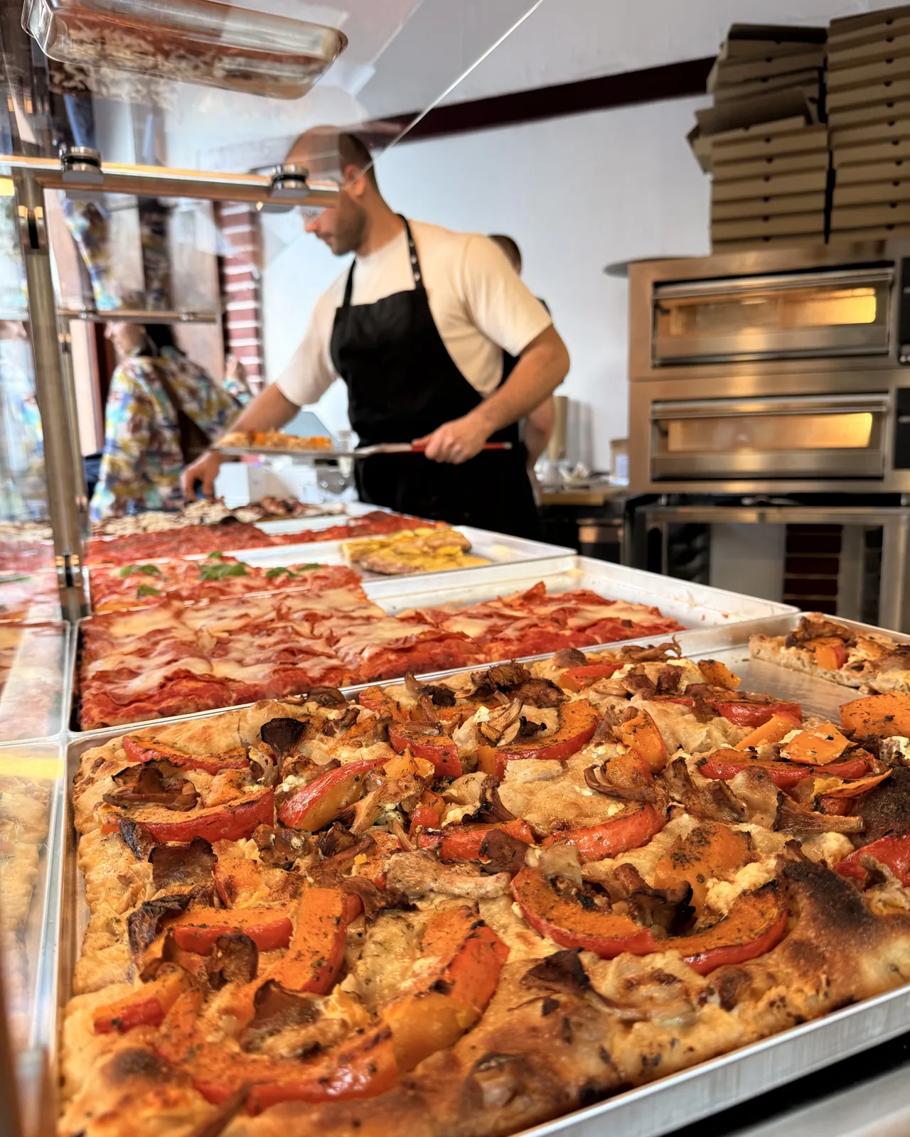 Pumpkin tray with feta and chanterelles, the pizzaiolo lifting a slice with the peel